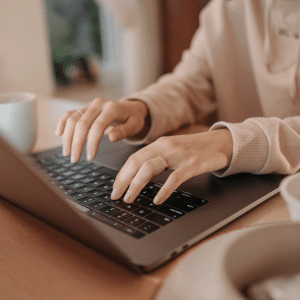 Person typing on a laptop with a coffee mug nearby