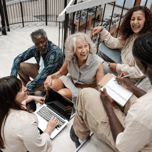 Group of adults smiling and learning with laptops and notebooks