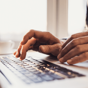 Close-up of hands typing on a laptop keyboard